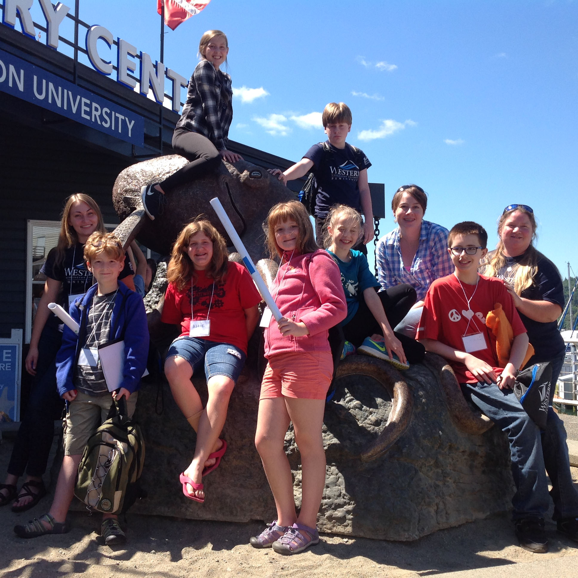 A group of students sit on and around a large octopus sculpture in front of the SEA center